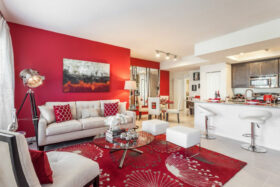 Living room with decorative rug, comfortable couches and chairs, and tripod mounted spotlight lamp.