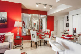 Living room and kitchen with smooth tile floors, decorative mirrors, and dining table with place settings.