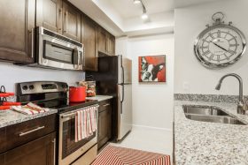 Kitchen with tile floors, rich wood cabinets, smooth stone countertops and stainless steel appliances.